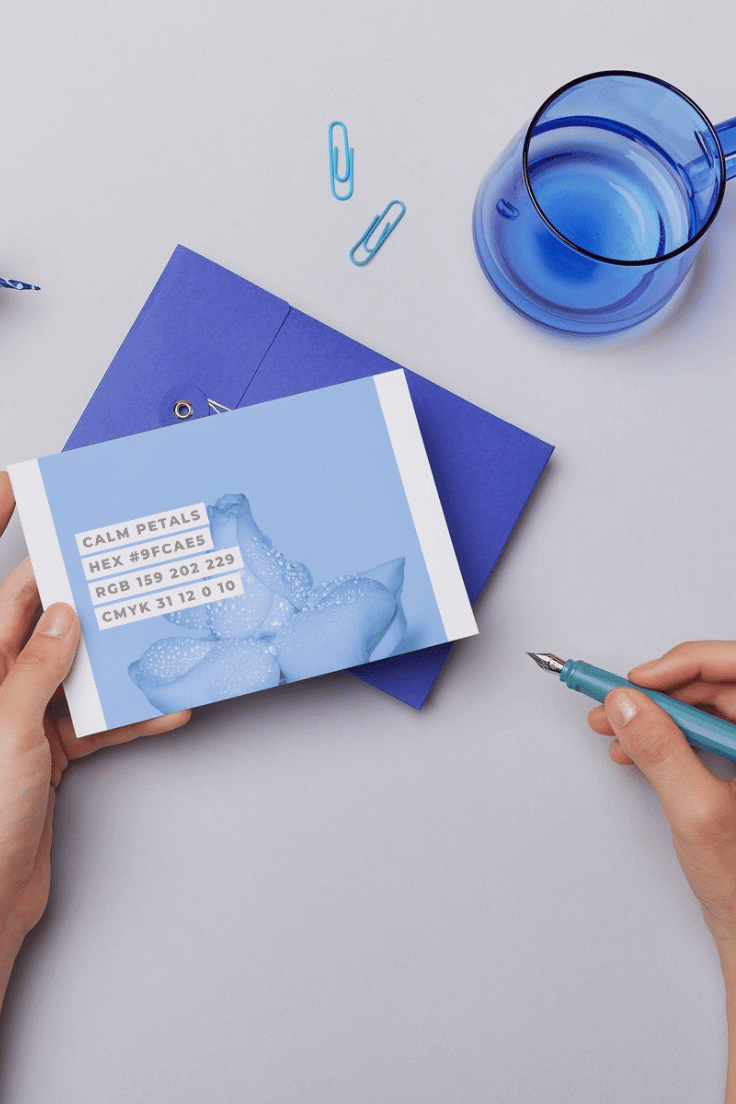 one hand holding a postcard of canva calming coastal color palette and another hand holding a pen